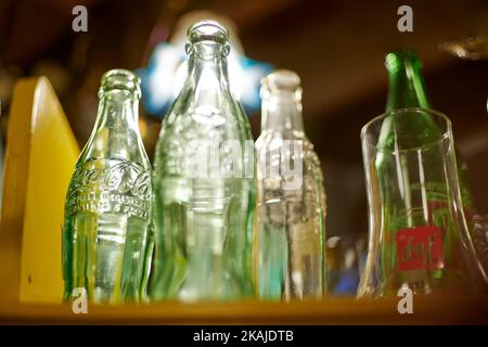 Eine selektive Aufnahme von Coca-Cola Flaschen und Gläsern unter heller Beleuchtung in einer Bar Stockfoto