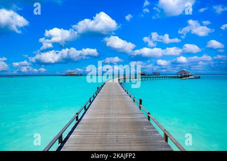 Ruhige meditative Lagune mit blauem, sonnigem Himmel. Idyllischer Naturblick mit langem Holzpier zur paradiesischen Insel, Luxus-Reiseziel Stockfoto