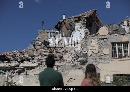 Ein Paar schaut auf, als Rettungskräfte versuchen, Überlebende am 24. August 2016 in Amatrice zu finden, nachdem ein starkes Erdbeben Mittelitalien erschüttert hat. Das Erdbeben hat mindestens 70 Tote gefordert, und die Gesamtzahl wird wahrscheinlich steigen, teilte die Katastrophenschutzeinheit des Landes bei der ersten offiziellen Todesrate mit. In Gemeinden in der Nähe des Epizentores des Bebens, das zwischen 6,0 und 6,2 eine Größenordnung hatte, wurden Dutzende von Gebäuden zu staubigen Steinhaufen reduziert. (Foto von Christian Minelli/NurPhoto) *** Bitte nutzen Sie die Gutschrift aus dem Kreditfeld *** Stockfoto