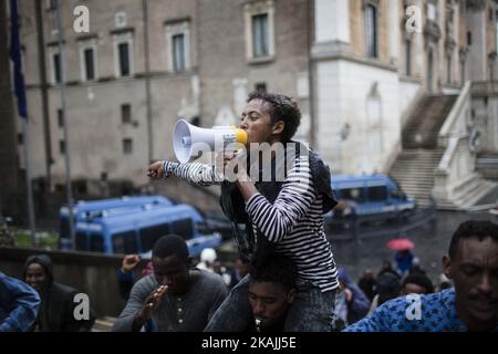 Junge Migranten rufen bei starkem Regen am 11. Oktober 2016 bei einer Demonstration auf dem Campidoglio-Platz auf dem Kapitolinischen Hügel im Zentrum Roms Parolen. Migranten und Freiwillige von "Baobab Experience" fragten nach einem sicheren Ort, an dem Flüchtlinge, hauptsächlich aus dem Horn von Afrika, untergebracht werden könnten.das Baobab-Zentrum wurde im Dezember 2015 von der Polizei nach den Anschlägen von Paris geschlossen. Doch die Baobab-Freiwilligen haben schnell ein Lager auf der Straße vor dem alten Tierheim mit Zelten und chemischen Toiletten eingerichtet, das drei Mahlzeiten am Tag serviert. (Foto von Christian Minelli/NurPhoto) *** Bitte nutzen Sie die Gutschrift von Cre Stockfoto