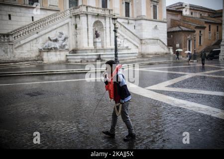 Ein junger Migrant pfeift, während er bei einem starken Regen mit einer Rettungsweste während einer Demonstration am 11. Oktober 2016 auf dem Campidoglio-Platz auf dem Kapitolinischen Hügel in Rom spaziert. Migranten und Freiwillige von "Baobab Experience" fragten nach einem sicheren Ort, an dem Flüchtlinge, hauptsächlich aus dem Horn von Afrika, untergebracht werden könnten.das Baobab-Zentrum wurde im Dezember 2015 von der Polizei nach den Anschlägen von Paris geschlossen. Doch die Baobab-Freiwilligen haben schnell ein Lager auf der Straße vor dem alten Tierheim mit Zelten und chemischen Toiletten eingerichtet, das drei Mahlzeiten am Tag serviert. (Foto von Christian Minelli/NurPhoto) *** Stockfoto