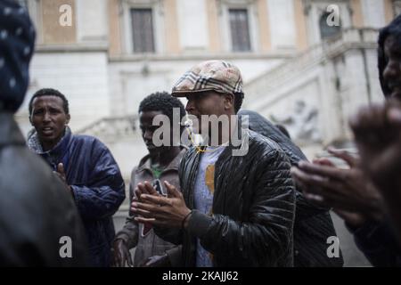 Junge Migranten rufen bei starkem Regen am 11. Oktober 2016 bei einer Demonstration auf dem Campidoglio-Platz auf dem Kapitolinischen Hügel im Zentrum Roms Parolen. Migranten und Freiwillige von "Baobab Experience" fragten nach einem sicheren Ort, an dem Flüchtlinge, hauptsächlich aus dem Horn von Afrika, untergebracht werden könnten.das Baobab-Zentrum wurde im Dezember 2015 von der Polizei nach den Anschlägen von Paris geschlossen. Doch die Baobab-Freiwilligen haben schnell ein Lager auf der Straße vor dem alten Tierheim mit Zelten und chemischen Toiletten eingerichtet, das drei Mahlzeiten am Tag serviert. (Foto von Christian Minelli/NurPhoto) *** Bitte nutzen Sie die Gutschrift von Cre Stockfoto