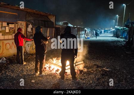 Migranten stehen im Dschungel von Calais an der Hauptstraße bei einem Brand. Das Flüchtlingslager an der Küste zum Ärmelkanal soll heute geräumt werden. Die rund 8.000 Flüchtlinge werden nach der Registrierung mit Bussen an verschiedene Aufnahmezentren in Frankreich verteilt. (Foto von Markus Heine/NurPhoto) *** Bitte nutzen Sie die Gutschrift aus dem Kreditfeld *** Stockfoto