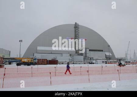 Arbeiter von Novarka überquert die Baustelle vor der neuen sicheren Enge, die über dem Reaktor der Einheit 4 in Tschornobyl errichtet wurde. Die neuen sicheren Einsperrungen der Sarkophage zerstörten am 29. November 2016 im Kernkraftwerk Chornobyl, Ukraine, den Reaktor 4.. Am 26. April haben 1986 Arbeiter des Kraftwerks unbeabsichtigt eine Kernschmelze im Reaktor verursacht. Er explodierte und schickte beim schlimmsten zivilen nuklearen Zwischenfall der Welt einen giftigen Cocktail radioaktiver Fallout in die Atmosphäre.der neue Safe Confinement-Sarkophag deckt am 29. November 2016 zerstörten Reaktor 4. im Kernkraftwerk Chornobyl ab Stockfoto