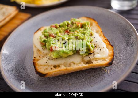 Gesundes Frühstück. Getoastetes italienisches Ciabatta-Brot mit geschmolzenem Käse und Avocado-Püree Stockfoto