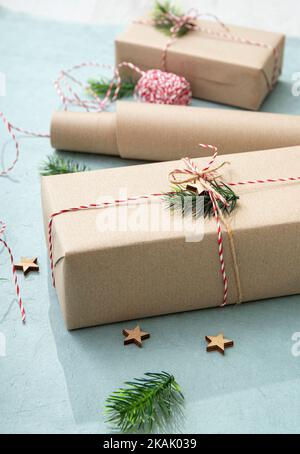 Geschenkverpackung mit natürlichem braunen Packpapier, genannt Sack Kraftpapier oder Sackpapier. Geschenke mit roter und weißer Papierschnur verziert. Stockfoto