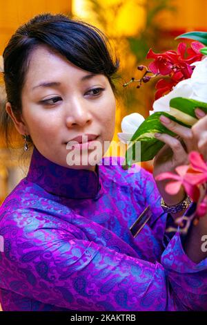 Vietnamesischer Rezeptionist, der Ao dai trägt und im Hotel in Ho Chi Minh City, Vietnam, arbeitet Stockfoto