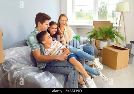 Junge Familie mit zwei Kindern hat Spaß in einer neuen Wohnung, in die sie gerade eingezogen sind. Stockfoto