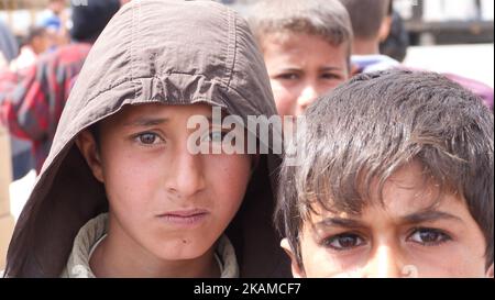 Kinder posieren im Lager Chamakor, östlich von Mosul, Irak, wo sich eine große Anzahl von Menschen niedergelassen hat, nachdem sie am 5. April 2017 im irakischen Hamam al-Alil, während der Offensive der irakischen Armee zur Rückeroberung der Stadt Mosul, vertrieben worden waren. Binnenvertriebene (IDP) waren im Lager Chamakor östlich von Mosul zu sehen, während der Kampf gegen den Islamischen Staat andauert. Seit der Eröffnung vor 3 Wochen leben mehr als 11 000 IDP im Lager. Das Lager ist so groß, dass die UNO eine neue Einrichtung für andere IDPs aus dem Westen von Mosul errichtet. Trockene Lebensmittelpakete werden verteilt, während die Menschen warten Stockfoto