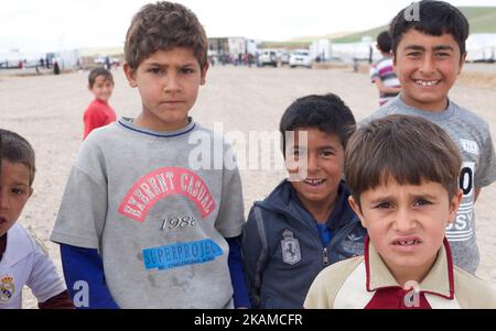 Kinder posieren im Lager Chamakor, östlich von Mosul, Irak, wo sich eine große Anzahl von Menschen niedergelassen hat, nachdem sie am 5. April 2017 im irakischen Hamam al-Alil, während der Offensive der irakischen Armee zur Rückeroberung der Stadt Mosul, vertrieben worden waren. Binnenvertriebene (IDP) waren im Lager Chamakor östlich von Mosul zu sehen, während der Kampf gegen den Islamischen Staat andauert. Seit der Eröffnung vor 3 Wochen leben mehr als 11 000 IDP im Lager. Das Lager ist so groß, dass die UNO eine neue Einrichtung für andere IDPs aus dem Westen von Mosul errichtet. Trockene Lebensmittelpakete werden verteilt, während die Menschen warten Stockfoto
