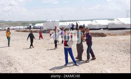Kinder posieren im Lager Chamakor, östlich von Mosul, Irak, wo sich eine große Anzahl von Menschen niedergelassen hat, nachdem sie am 5. April 2017 im irakischen Hamam al-Alil, während der Offensive der irakischen Armee zur Rückeroberung der Stadt Mosul, vertrieben worden waren. Binnenvertriebene (IDP) waren im Lager Chamakor östlich von Mosul zu sehen, während der Kampf gegen den Islamischen Staat andauert. Seit der Eröffnung vor 3 Wochen leben mehr als 11 000 IDP im Lager. Das Lager ist so groß, dass die UNO eine neue Einrichtung für andere IDPs aus dem Westen von Mosul errichtet. Trockene Lebensmittelpakete werden verteilt, während die Menschen warten Stockfoto