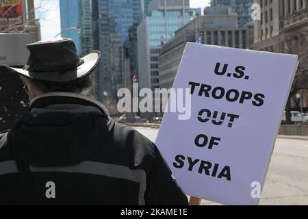 Der Mann hält ein Schild mit der Aufschrift „USA Truppen aus Syrien“ während eines Protestes gegen die Entscheidung des US-Präsidenten Donald Trump, am 8. April 2017 in Toronto, Ontario, Kanada, Luftangriffe gegen Syrien zu starten. Demonstranten versammelten sich vor dem amerikanischen Konsulat in Toronto, um die Luftangriffe gegen das syrische Regime in dieser Woche zu verurteilen. Die USA haben zum ersten Mal seit Beginn des Bürgerkriegs einen Raketenangriff auf Syrien gestartet, der auf einen Luftwaffenstützpunkt in der kleinen Stadt Idlib abzielte, von dem die Vereinigten Staaten behaupten, dass der Chemiewaffenangriff auf Zivilisten in dieser Woche vom Regime von Baschar al-Assad gestartet wurde. (Foto von C Stockfoto