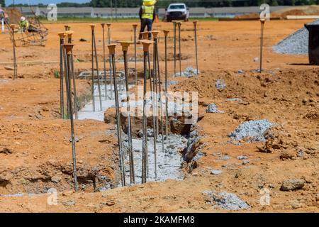 Es gibt eine Bewehrung mit Stahlstäben, die Drähte abschreckt, die während des Baus in Gräben für Betonfundamente gelegt werden Stockfoto