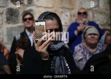 Eine orthodoxe christliche Gottesanbeterin filmt die Zeremonie zum „Waschen der Füße“ mit ihrem Telefon vor der Grabeskirche in der Jerusalemer Altstadt am 13. April 2017, Israel. (Foto von Corinna Kern/NurPhoto) *** Bitte nutzen Sie die Gutschrift aus dem Kreditfeld *** Stockfoto