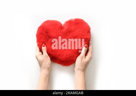 Frau Hände halten Fell roten Herzen isoliert auf weißem Hintergrund. Blick von oben. Grußkarte zum Valentinstag. Stockfoto