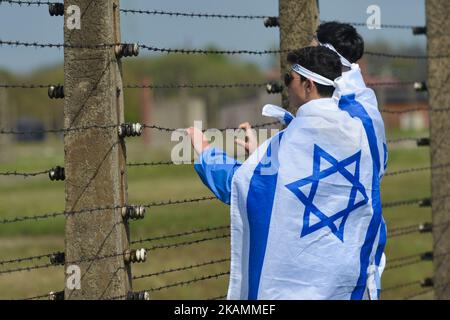 Zwei junge Teilnehmer schauen während des jährlichen Marsches von The Living Inside the former German Nazi Death Camp Auschwitz-Birkenau durch Stacheldrahtzaun Jüdische Menschen aus Israel und der ganzen Welt marschierten die Route 3km von Auschwitz nach Birkenau, zwischen zwei ehemaligen deutschen Nazi-Todeslagern, Als stilles Tribut an alle Opfer des Holocaust. Am Montag, den 24. April 2017, in Oswiecim, Polen. Foto von Artur Widak *** Bitte nutzen Sie die Gutschrift aus dem Kreditfeld *** Stockfoto