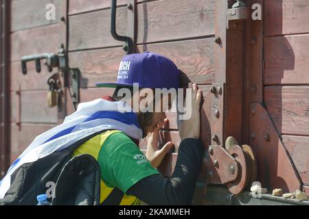 Ein junger Mann meditiert in der Nähe der Waggon-Gedenkstätte während des jährlichen Marsches des Lebens im ehemaligen deutschen Nazi-Todeslager Auschwitz-Birkenau Jüdinnen und Juden aus Israel und der ganzen Welt marschierten die Route 3km von Auschwitz nach Birkenau, zwischen zwei ehemaligen deutschen Nazi-Todeslagern, Als stilles Tribut an alle Opfer des Holocaust. Am Montag, den 24. April 2017, in Oswiecim, Polen. Foto von Artur Widak *** Bitte nutzen Sie die Gutschrift aus dem Kreditfeld *** Stockfoto