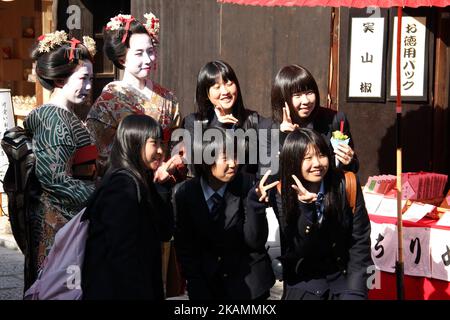 Asiatische Frauen, die sich als Geishas verkleidet haben, posieren mit einer Gruppe japanischer Schülerinnen in Kyoto, Japan Stockfoto