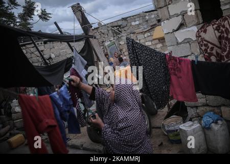 Eine palästinensische Flüchtlingsfrau wäscht sich während eines Stromausfalls im Flüchtlingslager Khanyounis im südlichen Gazastreifen in der Nähe eines Feuers Kleidung, am 23. April 2017. Die meisten Palästinenser im Gazastreifen verwenden Batterien, Generatoren oder Kerzen, um ihre Häuser anzuzünden. Die Bewohner von Gaza, wo rund 1,8 Millionen Menschen leben, erleben täglich rund 20 Stromausfälle. Berichten zufolge ging der einzige funktionierende Strom im Gazastreifen am 16. April 2017 aus dem Treibstoff und hörte auf zu arbeiten. Der Betrieb des Werks der Gaza Power Generating Company funktioniert in der Regel nur acht Stunden am Tag, nachdem der Brennstoff durch den israelischen Ker in den Gazastreifen eingedringen ist Stockfoto