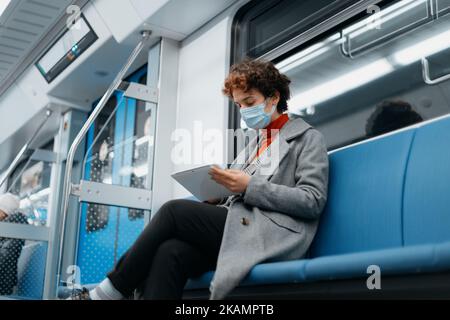 Junge Frau liest ein E-Book, während sie in einem U-Bahn-Auto sitzt. Stockfoto