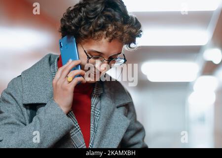 Frau, die auf ihrem Smartphone in einer leeren U-Bahn-Unterführung spricht. Stockfoto