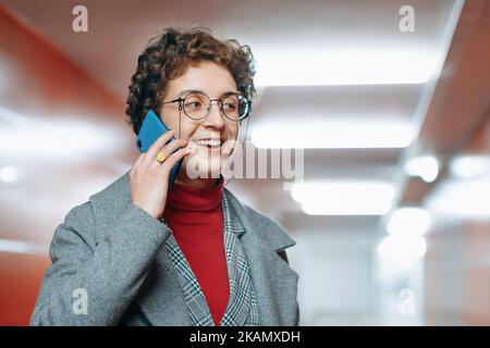 Frau, die auf ihrem Smartphone in einer leeren U-Bahn-Unterführung spricht. Stockfoto