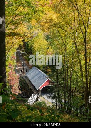 Eine vertikale Aufnahme einer rot bedeckten Brücke in Flume Gorge Trek, Franconia Notch Park, New Hampshire Stockfoto