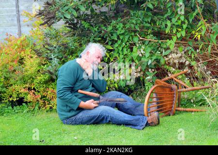 Älterer Mann im Garten und hatte einen Unfall. Umgefallen. Unfall. Scharfe Schere in der Hand. Alter Mann verletzt. Stockfoto