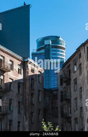 Alte verlassene Häuser auf dem Hintergrund moderner, hoher Glasgebäude. Stockfoto
