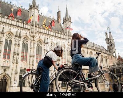 Am 27. Mai 2017 fahren Menschen mit dem Fahrrad zwischen historischen Architekturen durch eine Straße in Brügge, Belgien. An einem der wärmsten Tage des Jahres wurde Brügge von Tausenden von Touristen aus der ganzen Welt ausgewählt. Dies ist die Hauptstadt und größte Stadt der Provinz Westflandern in der flämischen Region Belgiens, im Nordwesten des Landes. Da Brügge ein riesiges Touristenziel ist, haben Touristen eine große Auswahl, um die Stadt zu genießen, wie Pferdekutschenfahrten, Grachtenfahrten mit dem Boot oder einfach nur einen Spaziergang durch das historische Stadtzentrum. (Foto von Romy Arroyo Fernandez/Nu Stockfoto