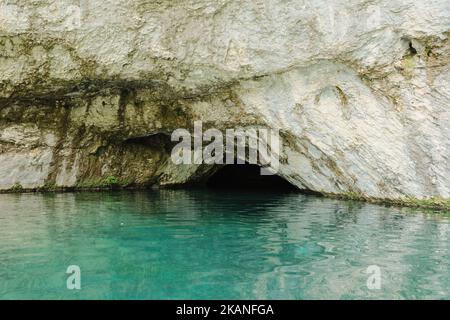 Der Eingang einer kleinen Höhle über dem klaren türkisfarbenen Wasser im Nationalpark Plitvice Stockfoto