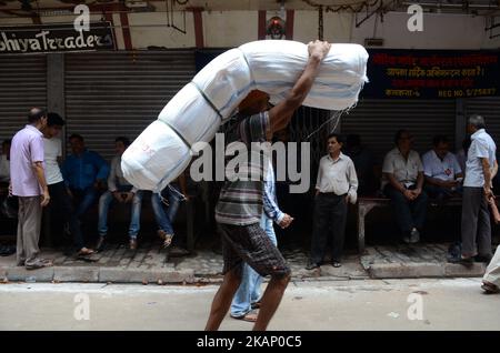 Ein indischer Arbeiter, der Waren transportiert, geht am Donnerstag, 29.. Juni 2017, während des Streiks gegen GST in Kalkutta, Indien, am geschlossenen Laden in Burrabazar vorbei. Tuchhändler gehen ab 27. Juni zu einem dreitägigen landesweiten Streik, um gegen 5 Prozent GST (Waren- und Dienstleistungssteuer) zu protestieren, die auf die von ihnen erbrachten Dienstleistungen (Arbeitsleistungen) für die Textilindustrie erhoben werden.Textilhändler protestieren gegen eine komplexe, verwirrende GST (Waren- und Dienstleistungssteuer) Regeln im ganzen Land. (Foto von Sonali Pal Chaudhury/NurPhoto) *** Bitte nutzen Sie die Gutschrift aus dem Kreditfeld *** Stockfoto