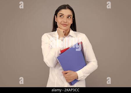 Studentin hält Bücher isoliert auf grauem Hintergrund im Studio. Englische Sprachschule, Bildungskonzept. Denkender Student. Stockfoto