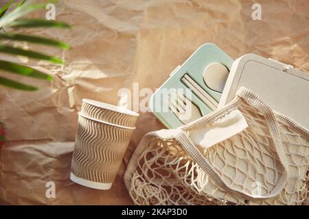 Plastikfreies, umweltfreundliches ökologisches Geschirr in wiederverwendbarem Beutel auf zerknittertem Papier. Nachhaltiger Lebensstil. Stockfoto