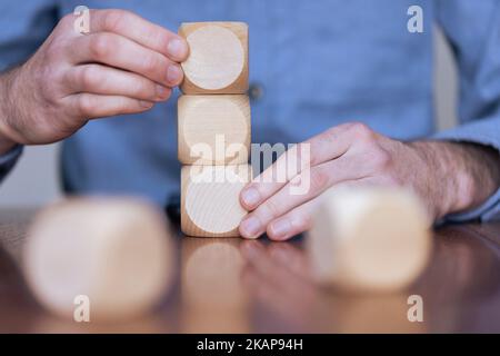 Nahaufnahme eines Geschäftsreisenden, der große Holzblöcke arrangiert. Geschäftsstrategie und -Lösungen Stockfoto