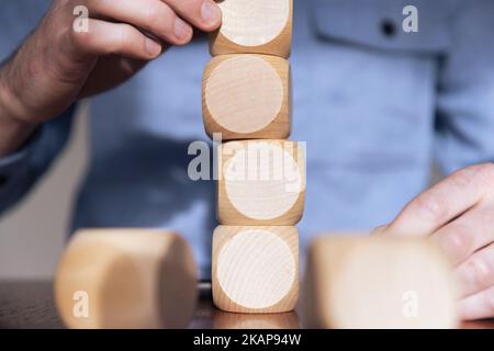 Nahaufnahme eines Geschäftsreisenden, der große Holzblöcke arrangiert. Geschäftsstrategie und -Lösungen Stockfoto