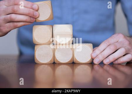 Nahaufnahme eines Geschäftsreisenden, der große Holzblöcke arrangiert. Geschäftsstrategie und -Lösungen Stockfoto