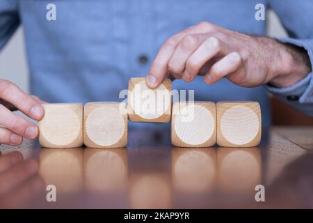 Nahaufnahme eines Geschäftsreisenden, der große Holzblöcke arrangiert. Geschäftsstrategie und -Lösungen Stockfoto