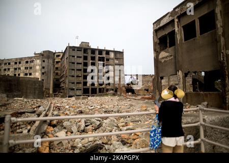 Touristen schauen sich am 8. August 2017 einen Teil der Insel Hashima an, der allgemein als Gunkanjima oder „Schlachtschiffinsel“ in der Präfektur Nagasaki im Süden Japans bekannt ist. Die Insel war bis zu ihrer Schließung im Jahr 1974 ein Kohlebergbaubetrieb und ist ein Symbol für die schnelle Industrialisierung Japans, die auch an ihre dunkle Geschichte als Ort der Zwangsarbeit während des Zweiten Weltkriegs erinnert. Die Insel ist heute als UNESCO-Weltkulturerbe der japanischen Meiji-Industriellen Revolution anerkannt. (Foto von Richard Atrero de Guzman/NurPhoto) *** Bitte nutzen Sie die Gutschrift aus dem Kreditfeld *** Stockfoto