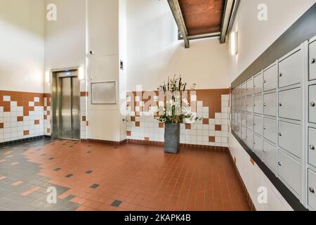 Aufzug mit geöffneter Tür in beleuchteter Halle des modernen Apartmentgebäudes mit Postfächern Stockfoto