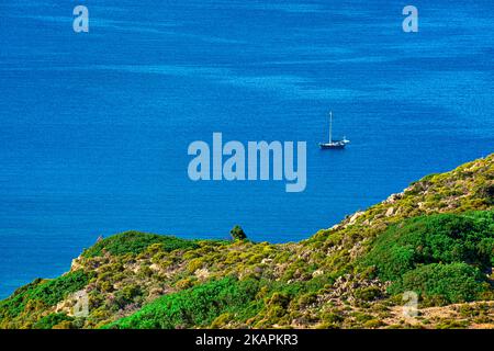 Ein Segelboot in ruhigen Gewässern am grünen Inselhügel, Luftaufnahme. Sommerferien, Wandern, Segeln, Abenteuer, Kurzurlaub. Stockfoto