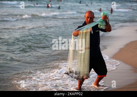 Der palästinensische Fischer Jihad al-Soltan (R) bereitet sein Fangnetz an einem Strand im nördlichen Gazastreifen vor, 21. August 2017. (Foto von Majdi Fathi/NurPhoto) Stockfoto