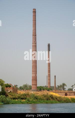 Industriekamine aus gemusterten roten Ziegeln am Ufer des Nils, Ägypten Stockfoto