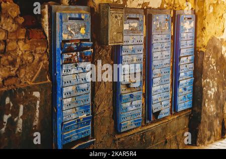 Kaputte alte rostige Briefkästen. Blick auf alte Briefkästen, die an einer schmutzigen, beschädigten Wand hängen. Stockfoto