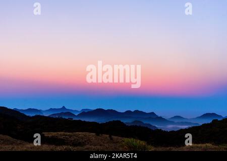 Ein atemberaubender Blick auf die geschichtete Bergkette während des rosa und blauen Sonnenaufgangs Stockfoto
