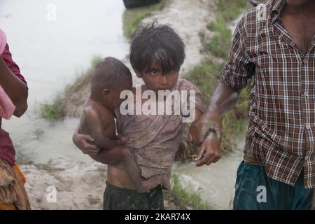 08. September 2017 Takenuf, Bangladesch - Rohingya-Menschen, die vor laufenden Militäroperationen im birmanischen Rakhine-Staat geflohen sind, machen sich am 2017. September durch schlammiges Wasser auf, nachdem sie die Grenze zwischen Bangladesch und Myanmar in Teknuf, Bangladesch, überquert haben. Nach Angaben der Vereinten Nationen sind seit Ausbruch der jüngsten Krise im Bundesstaat Rakhine in Myanmar bereits mehr als 370000 Flüchtlinge nach Bangladesch geflohen. Am 25. August kam es im Rakhine-Staat in Myanmar zu Gewalt, als die Sicherheitskräfte des Landes eine Operation gegen die muslimische Rohingya-Gemeinschaft starteten. Es löste einen neuen Zustrom von Flüchtlingen in Nachbarschaftspolitik aus Stockfoto