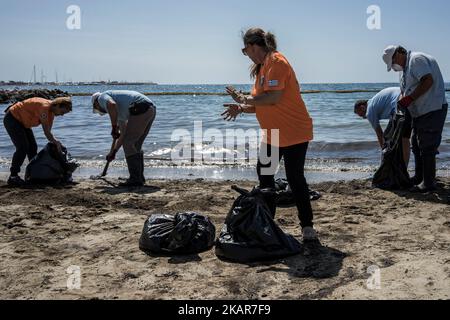 Stadtarbeiter versuchen zusammen mit Freiwilligen, die Ölpest des griechischen Tankers Agia Zoni II, der vor der Insel Salamis an den Stränden von Glyfada und anderen Teilen der Riviera von Athen versank, einzudämmen. Athen, Den 14. September 2017. Der kleine Tanker 'Agia Zoni II' sank am 10. September, während er vor der Küste von Salamis in der Nähe des griechischen Haupthafens Piräus vor Anker ging. Es trug eine Ladung von 2.200 Tonnen Heizöl und 370 Tonnen Meeresgasöl. Die Insel Salamis wurde durch eine von Beamten so genannte „große Umweltkatastrophe“ stark verschmutzt. (Foto von Kostis Ntanta Stockfoto