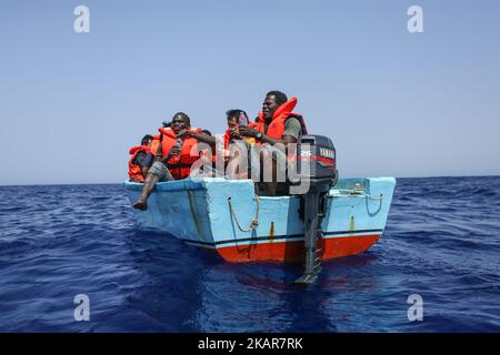 LAMPEDUSA, ITALIEN - SEPTEMBER 02: Flüchtlinge und Migranten warten darauf, von einem überfüllten kleinen Holzboot zu einem Irischen Kriegsschiff überführt zu werden, nachdem sie von Such- und Rettungscrew-Mitgliedern der deutschen NGO Sea-Eye etwa 46 Seemeilen (nm) von einem überfüllten kleinen Holzboot unterstützt und mit Rettungswesten und Trinkwasser versorgt wurden 2, 2017. Die Sicherheitslage für SAR-NGOs wie Sey-Eye hat sich verschlechtert, nachdem die so genannte libysche Kostengarde ihr Such- und Rettungsgebiet von 12nm auf 72nm erweitert hat. Gleichzeitig hat die Zahl der geretteten Menschen aus der Not von NGOs b Stockfoto