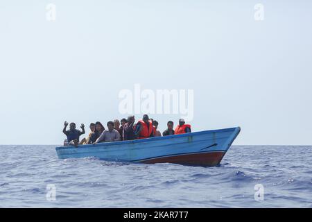 LAMPEDUSA, ITALIEN - 02. SEPTEMBER: Flüchtlinge und Migranten werden in einem überfüllten kleinen Holzboot schwimmend gesehen, während sie auf Hilfe von Such- und Rettungscrew-Mitgliedern der deutschen NGO Sea-Eye warten, nachdem sie am 2. September 2017 etwa 46 Seemeilen (nm) in libysch eingeweihten Gebieten aufgefunden wurden. Die Sicherheitslage für SAR-NGOs wie Sey-Eye hat sich verschlechtert, nachdem die so genannte libysche Kostengarde ihr Such- und Rettungsgebiet von 12nm auf 72nm erweitert hat. Gleichzeitig wurde die Zahl der geretteten Menschen aus der Not von NGOs aufgrund dieser Tatsache abgelehnt. (Bild: Stockfoto