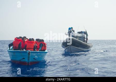 LAMPEDUSA, ITALIEN - SEPTEMBER 02: Flüchtlinge und Migranten warten auf den Transfer von einem überfüllten kleinen Holzboot zu einem irischen Kriegsschiff, nachdem sie von Such- und Rettungscrew-Mitgliedern der deutschen NGO Sea-Eye etwa 46 Seemeilen (nm) von einem überfüllten kleinen Boot aus Holz unterstützt und mit Rettungswesten vorbereitet wurden. 2 2017 Die Sicherheitslage für SAR-NGOs wie Sey-Eye hat sich verschlechtert, nachdem die so genannte libysche Kostengarde ihr Such- und Rettungsgebiet von 12nm auf 72nm erweitert hat. Gleichzeitig wurde die Zahl der geretteten Menschen aus der Not von NGOs aufgrund der Zahlen zurückgegangen Stockfoto